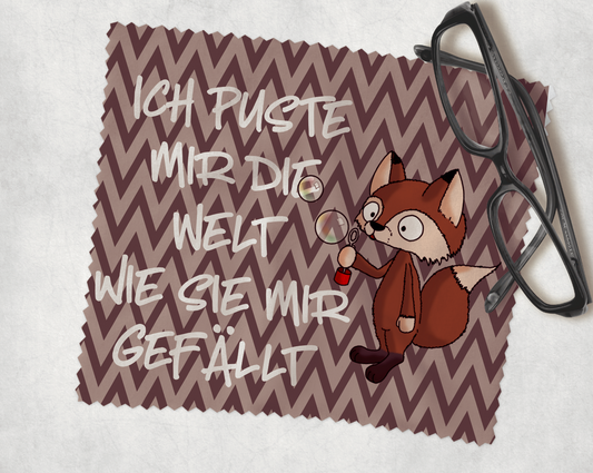 Brillenputztuch in grün mit einem Comic Fuchs der Seifenblasen pustet und dem Text Ich puste mir die Welt wie sie mir gefällt mit braunem hintergrund